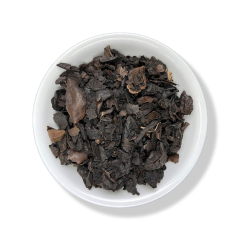 A bowl filled with black walnut hulls on a white background.
