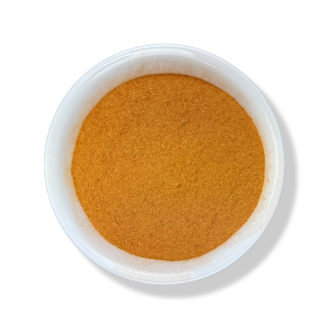 A bowl filled with finely ground orange-brown powder, traditionally used as a herbal supplement.