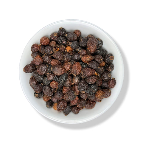 Dried Rose Hips in a white bowl on a white background.