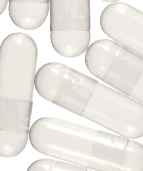 A collection of empty white vegetable capsules meant for custom blending with herbal powder.
