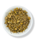 A bowl of dried chamomile flowers, Matricaria recutita, with a background suitable for wellness and relaxation themes.