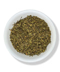 A bowl of dried Chaparral (Larrea tridentata) leaves, commonly known as Gobernadora, against a white background.
