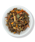 A variety of dried herbal tea leaves and pieces in a white bowl.