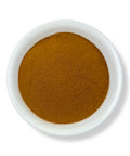 A white bowl filled with brown cloves powder on a white background.