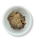 Dried Jericho Flower (Doradilla) curled into a ball, displayed in a white bowl.
