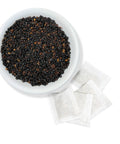 A bowl filled with elderberries, with several tea bags placed beside it