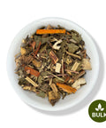 A bowl of dried herbal tea blend, including pieces of fennel, mugwort, and other herbs.
