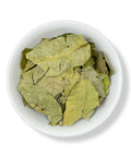 A bowl filled with dried leaves of Zapote Blanco (White Sapote) against a white background.