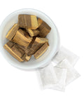 Palo Azul wood chunks in a white bowl with three herbal tea bags beside it