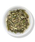 A bowl filled with dried olive leaf pieces on a white background.