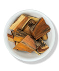 Dried Palo Brazil wood chunks in a white bowl on a white background.