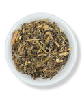A variety of dried herbal tea leaves and pieces in a white bowl.