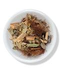 A bowl of dried herbal tea ingredients including pieces of bark, leaves, and roots.