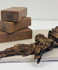 Three stacked soap bars with a piece of wood on a white background