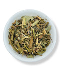 A variety of dried herbal tea leaves and pieces in a white bowl.