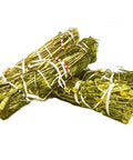 Two cylindrical chamomile flower rolls, tightly bound with string, displaying green chamomile flowers and bounding edges.