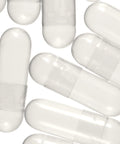 A collection of empty white vegetable capsules meant for custom blending with herbal powder.