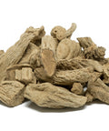 Dried valerian root pieces in a loose pile on a white surface.